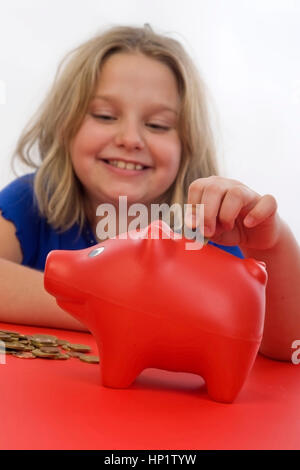 Modello di rilascio , Maedchen, 8 Jahre, fuettert Sparschwein - ragazza con salvadanaio Foto Stock