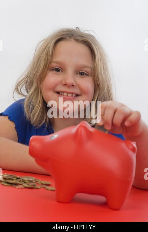 Modello di rilascio , Maedchen, 8 Jahre, fuettert Sparschwein - ragazza con salvadanaio Foto Stock