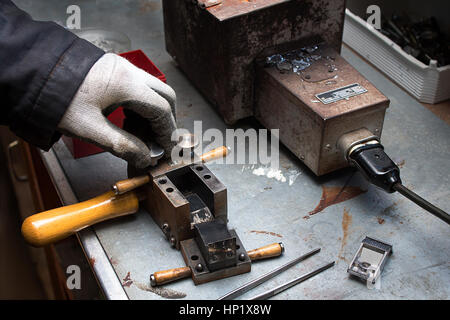 Impianto di artigiano produce componenti per le macchine. Manifattura, produzione manuale di lega di piombo un dipendente dello stabilimento craft durante il lavoro. Foto Stock