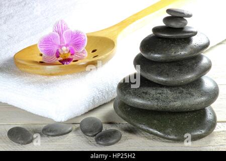 Pietre di basalto per massaggio hot stone con accessori su sfondo di legno Foto Stock