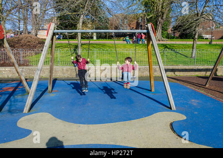 Fratelli giocando su oscilla in un bambini;s parco giochi. Foto Stock