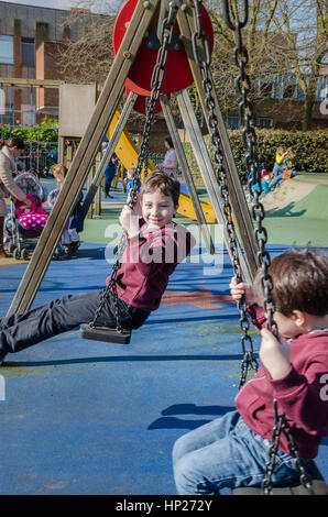 I fratelli giovani giocando su oscilla in un parco giochi per bambini. Foto Stock