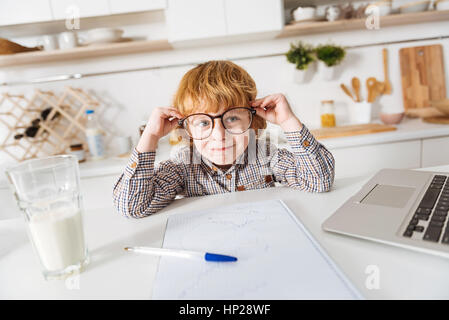 Lo zenzero affascinante ragazzo seduto in una cucina soleggiato Foto Stock