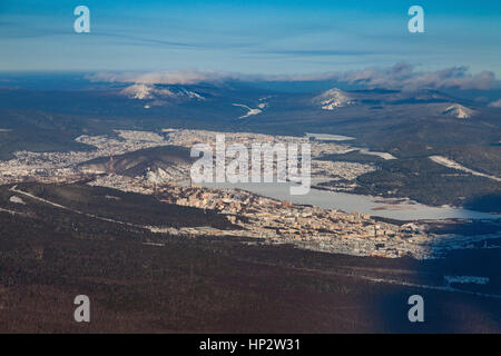 Vista da sopra del centro industriale degli Urali città di Zlatoust in inverno, circondato da montagne invernali. Foto Stock