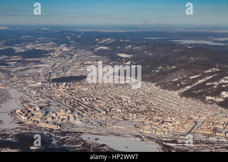 Vista da sopra del centro industriale degli Urali città di Miass in inverno, circondato da montagne invernali. Foto Stock