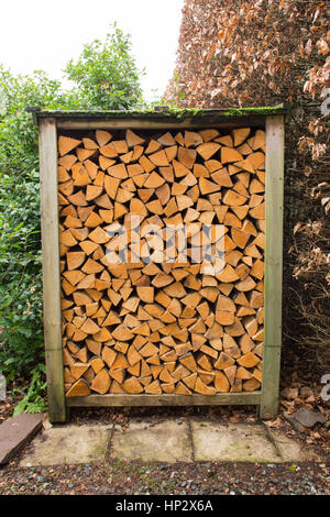 Legna da ardere - forno-essiccato condito split tronchi di legno duro per stufa a legna bruciatore di legno impilate ordinatamente nel piccolo regno unito giardino negozio di legno Foto Stock