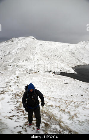 Maschio solitario Walker salendo nella neve per Esk Hause con angolo Tarn e la Wainwright Rossett Pike dietro ,Langdale,Parco Nazionale del Distretto dei Laghi, Foto Stock