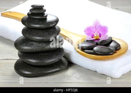 Pietre di basalto per massaggio hot stone con accessori su sfondo di legno Foto Stock