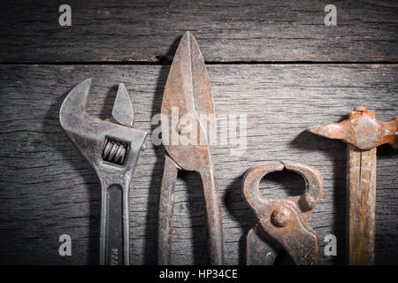 Vecchi strumenti di fabbro su un grigio e incrinato sfondo di legno. Spazio per il testo. Vista da sopra. Foto Stock