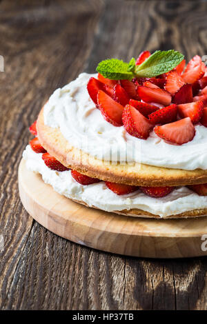 In casa sullo strato di crema dolce, fresco e colorato e delizioso dessert con succose fragole e il dolce di panna montata. Foto Stock