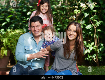 Giocare nel parco giovane famiglia con due bambini piccoli nel parco verde di sfondo Foto Stock