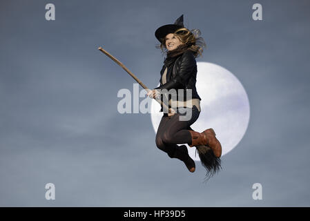 Strega donna battenti sul suo besom Foto Stock