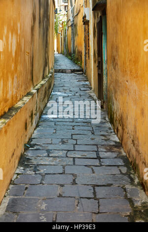 Ciottoli e pareti gialle in vicolo, Hoi An (Patrimonio Mondiale dell'UNESCO), Vietnam Foto Stock