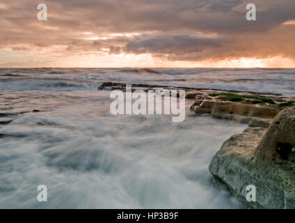 Onde in rotolamento come la marea sale all'alba sulla costa nordorientale del Regno Unito Foto Stock