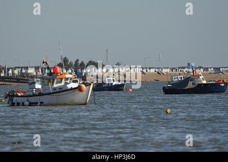 Thorpe Bay beach, Essex, sull'estuario del Tamigi, con una lunga fila di cabine sulla spiaggia, e barche ormeggiate Foto Stock