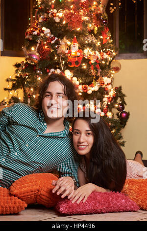 Sposato giovane coppia albero di Natale la posa accanto a ciascun altro Foto Stock