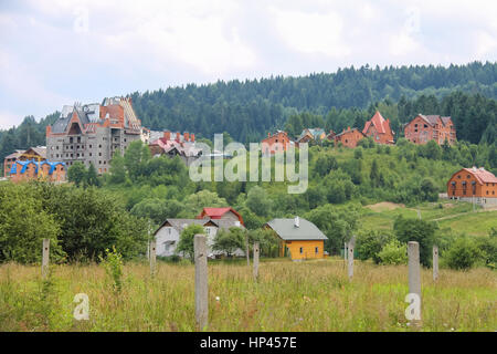 Modern cottages on slopes of forested mountains. Carpathians, Ukraine Foto Stock