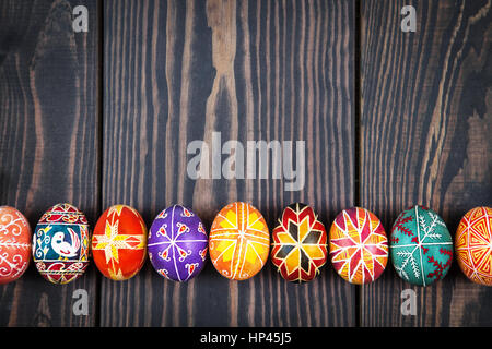 Uova di Pasqua in fila su di un legno scuro dello sfondo. Foto Stock