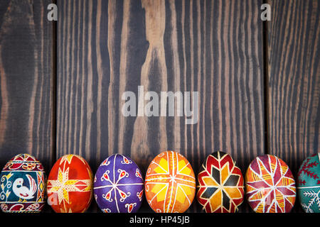 Uova di Pasqua in fila su di un legno scuro dello sfondo. Foto Stock