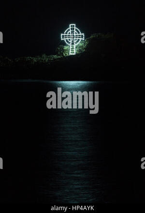 Croce illuminata riflessa sul mare di notte, Mousehole le luci di Natale, Cornwall, Regno Unito Foto Stock