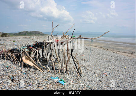 Spiaggia arte scultura o riparo fatto da driftwood, spazzatura e lavato fino flotsam sulla riva Black Rock sands beach vicino al villaggio gallese di Morfa Foto Stock