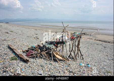 Spiaggia arte scultura o riparo fatto da driftwood, spazzatura e lavato fino flotsam sulla riva Black Rock sands beach vicino al villaggio gallese di Morfa Foto Stock