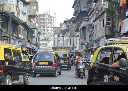 Mumbai, India - 10 Ottobre 2015 - Uomo pacchetto trasporta sulla sua testa muovendo lentamente in molto affollate strade e traffico in Kochi con tuk tuk e imposte Foto Stock