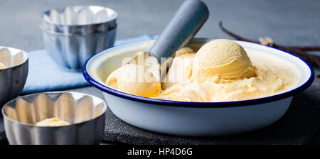 In casa la vaniglia e caramello gelato in vaschetta vintage. Prodotto organico su una pietra grigia sullo sfondo. Foto Stock