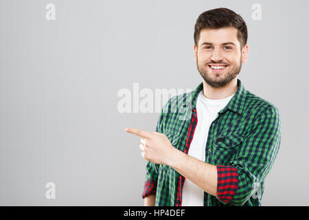 Uomo in verde controllata T-shirt puntando verso qualcosa di Foto Stock