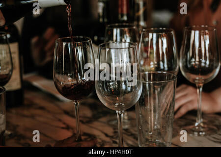 Vino rosso che viene colato con occhiali altri. Foto Stock