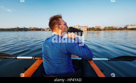 L'uomo galleggiante sul lago in un kayak al fantastico tramonto. Foto Stock