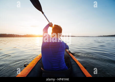 L'uomo galleggiante sul lago in un kayak al fantastico tramonto. Foto Stock