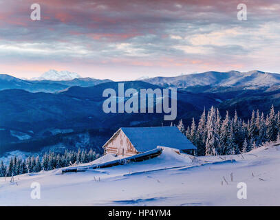 Fantastico tramonto su montagne innevate e chalets in legno Foto Stock