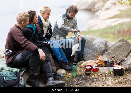 Amici guardando l'uomo macinazione di caffè al campeggio Foto Stock