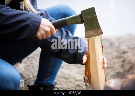 La donna il taglio di legna per il falò in campeggio Foto Stock