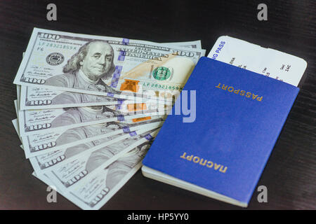Vista superiore del passaporto con banconote di dollari sulla scrivania in legno Foto Stock
