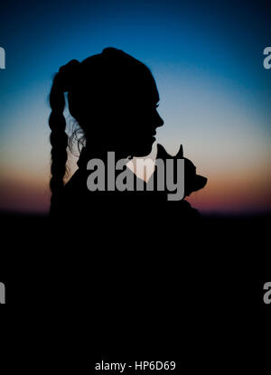 Silhouette della ragazza e il suo cagnolino sul tramonto. Bellissimo cielo gradiente. Foto Stock