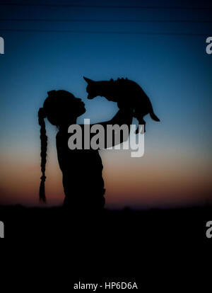 Silhouette della ragazza e il suo cagnolino sul tramonto. Bellissimo cielo gradiente. Foto Stock