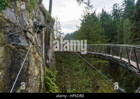 Vancouver, Canada - 28 Gennaio 2017: un ponte di sospensione pendenti da una scogliera alta al di sopra del canyon presso il Ponte Sospeso di Capilano Park Foto Stock