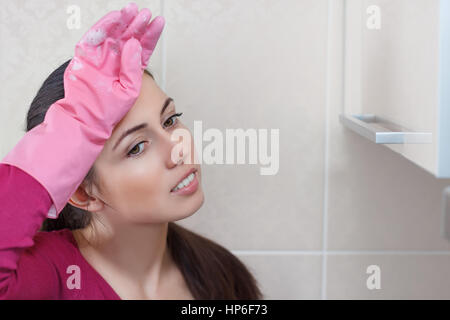 Stanco bella donna caucasica nei guanti di protezione dopo la pulizia. Femmina stanco dopo i lavori domestici Foto Stock