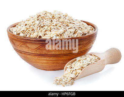 Fiocchi di avena nel recipiente di argilla e scoop di legno isolato su uno sfondo bianco. Cibo sano. Semole e semolini di sano. Vaso in ceramica con cereali. I fiocchi d'avena Foto Stock