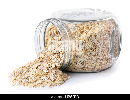 Vetro trasparente jar con fiocchi d'avena isolati su sfondo bianco. Vaso di vetro con fiocchi di avena giacente sul lato isolato su sfondo bianco. Scatter Foto Stock