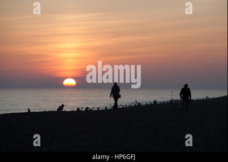 La gente si stagliano contro un bel tramonto mentre stanno sulla spiaggia a Worthing in West Sussex, Regno Unito. Foto Stock