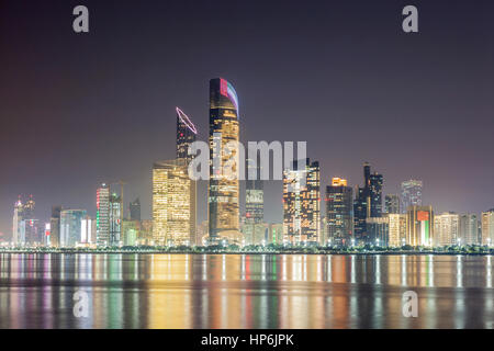 Skyline di Abu Dhabi downtown illuminata di notte. Emirati Arabi Uniti, Medio Oriente Foto Stock