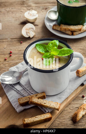 Zuppa di funghi con crostini e basilico in tazza di metallo su legno rustico sfondo - sani in casa Organica Vegana Vegetariana deliziosa zuppa pasto pranzo f Foto Stock