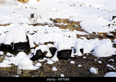 Primo piano in pietra e neve nella nebbia Noboribetsu Onsen neve invernale del parco nazionale di Jigokudani, Hokkaido, Giappone Foto Stock