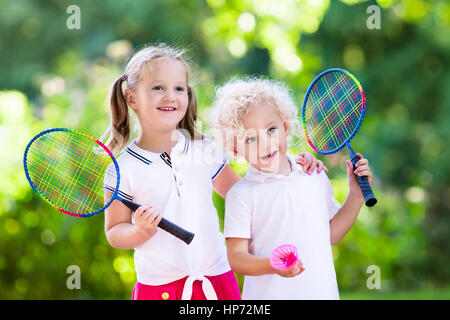 Attiva la ragazza in età prescolare e ragazzo giocando badminton in tribunale aperto in estate. I bambini a giocare a tennis. Scuola di sport per i bambini. Racchette e volano spor Foto Stock