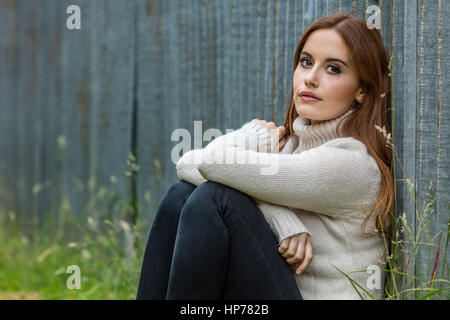 Outdoor ritratto della bella ragazza pensosa o una giovane donna con i capelli rossi che indossa un ponticello bianco Foto Stock