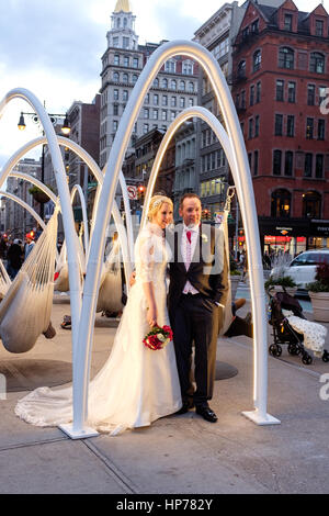 Giovane che posano per una foto di matrimonio a Flatiron Skyline, sei amache sospesa da dieci arcate di acciaio durante il 2016 vacanze di Natale, a plaza accanto a Ma Foto Stock