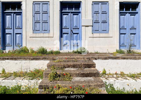Chiuso blu pannellate in legno Porte-persiane alle finestre del Nikolaos Stamatiou scuola primaria aperta nel 1903 costruita di pietra su sunken cortile di San Foto Stock
